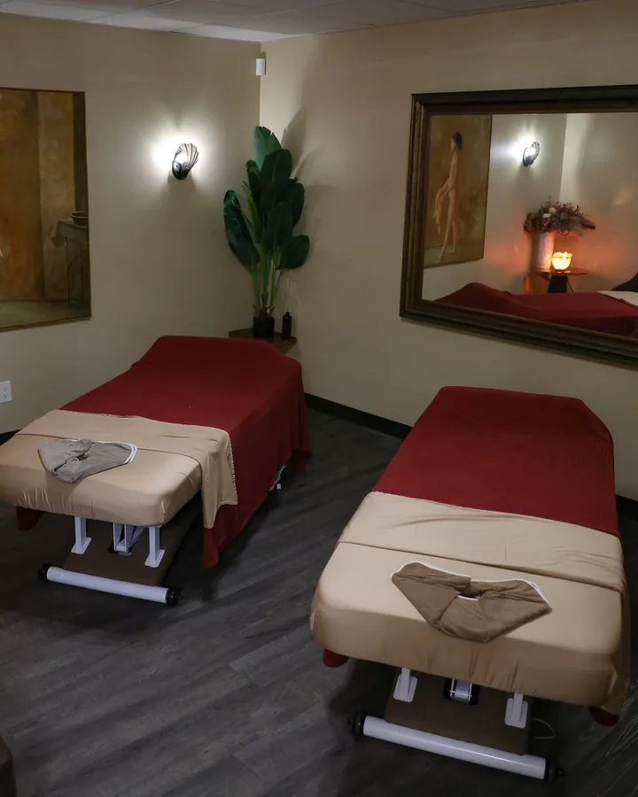 Side-by-side massage tables beneath a large mirror in the couples suite